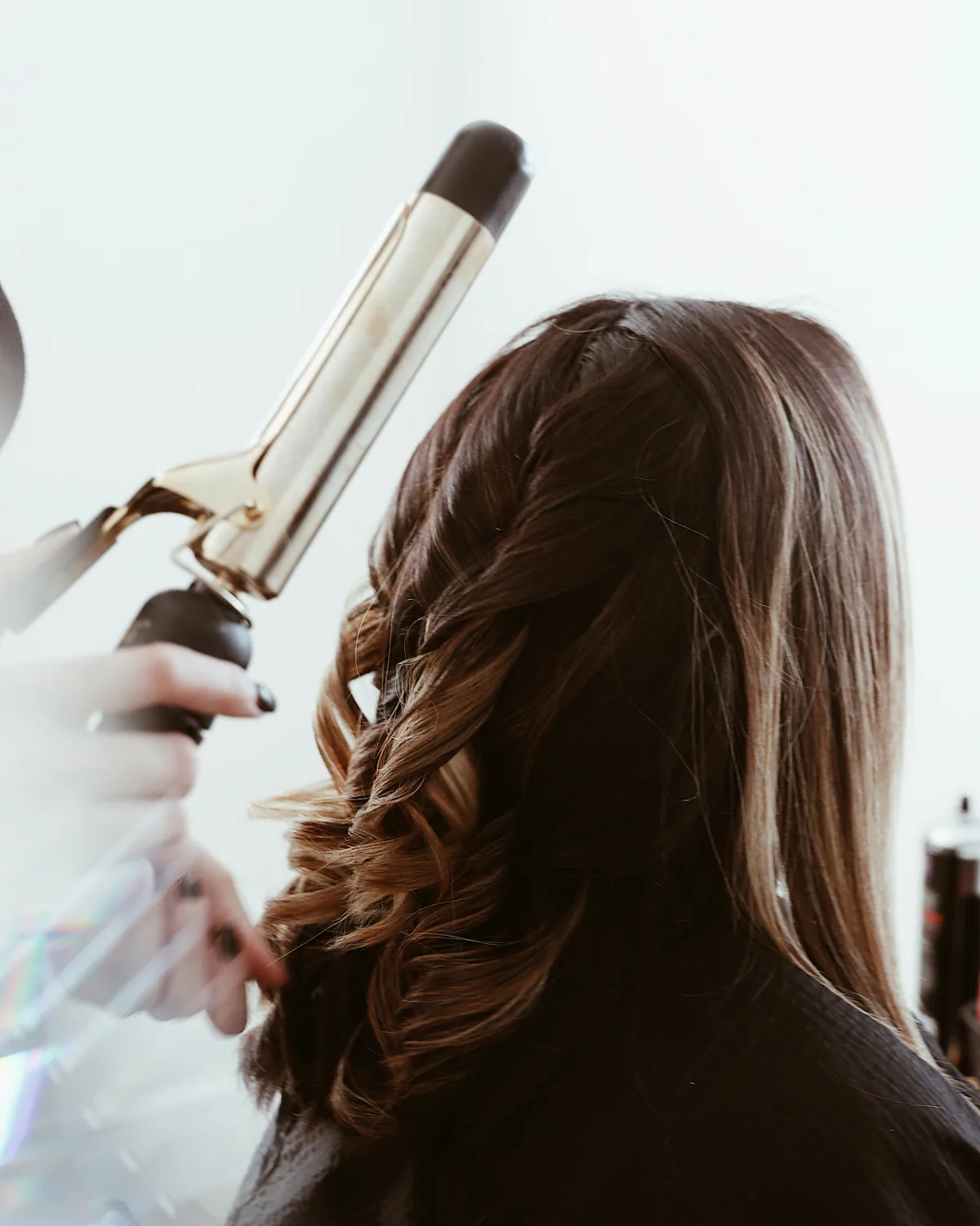 Long brown hair being curled with a styling iron