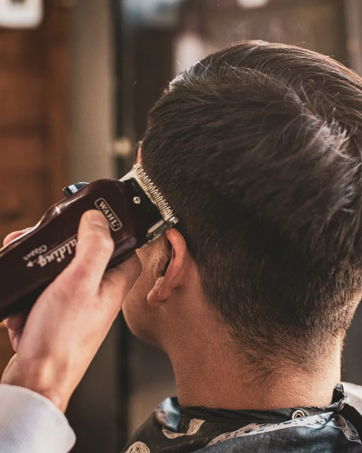 A stylist sectioning a client's dark hair at the chair
